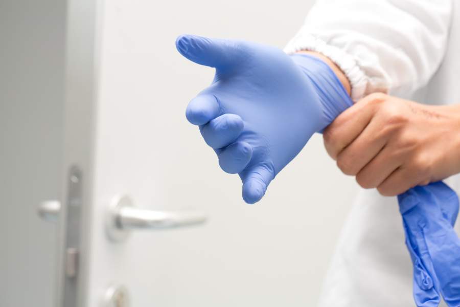 La personne porte des gants de caoutchouc (équipement de protection individuelle) en laboratoire.
