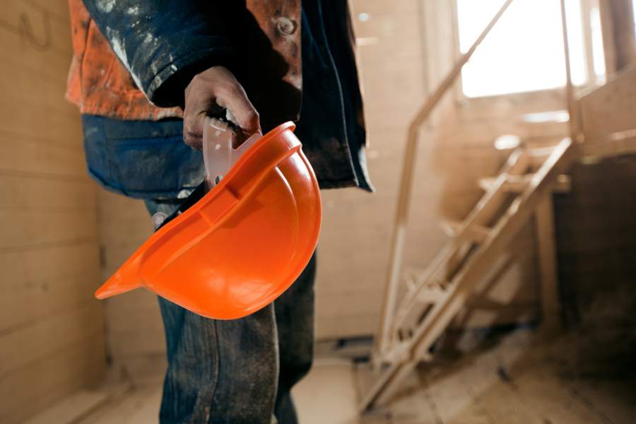 Un ouvrier tient un nouveau casque orange à la main sur le chantier de construction